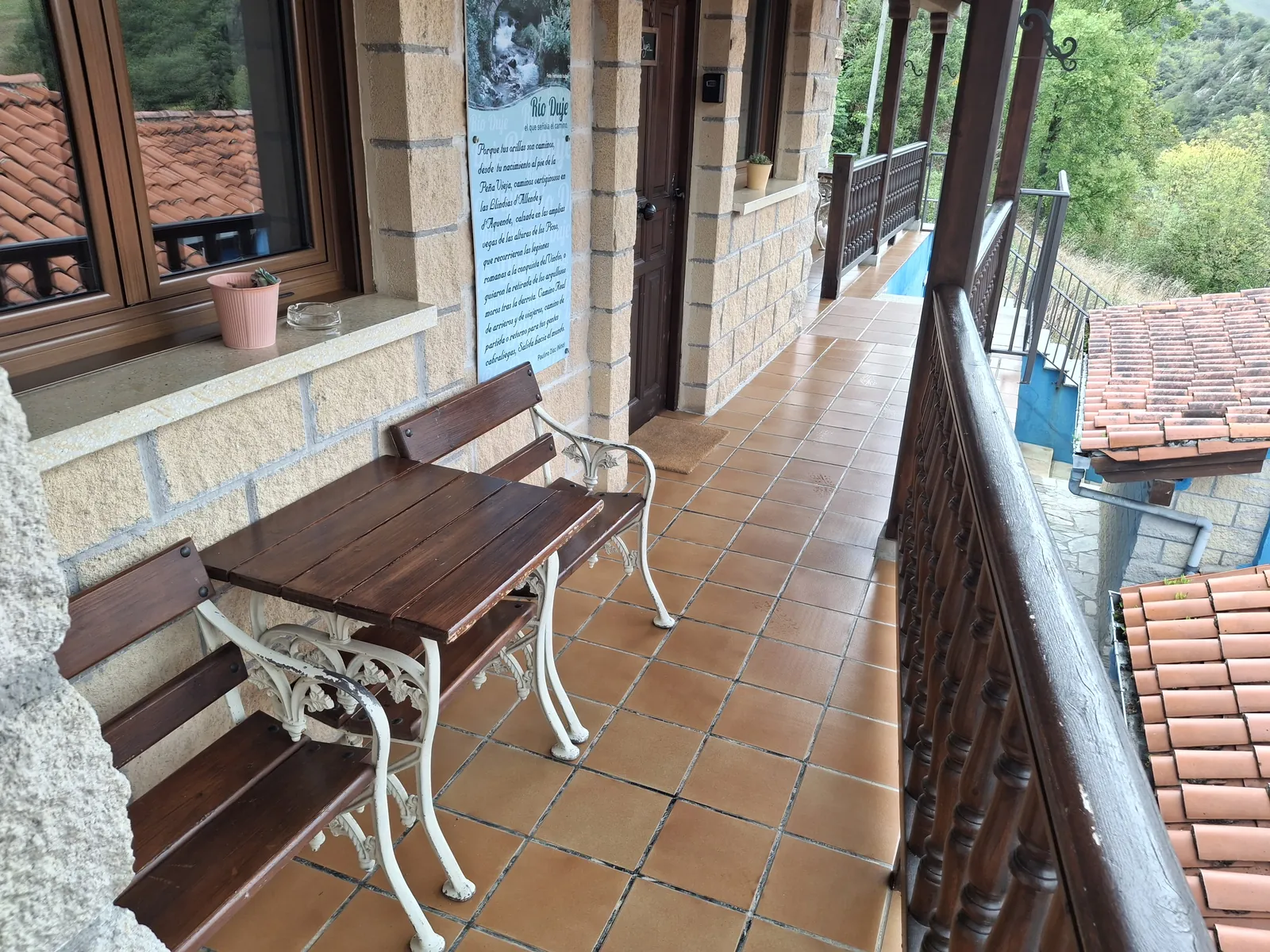 Galería cubierta común frente al apartamento Duje, con banco, mesa y barandilla de madera