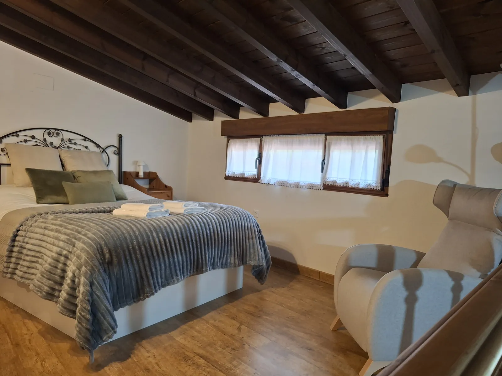 Bedroom on the mezzanine of La Casina, under timber beams and open to the floor below