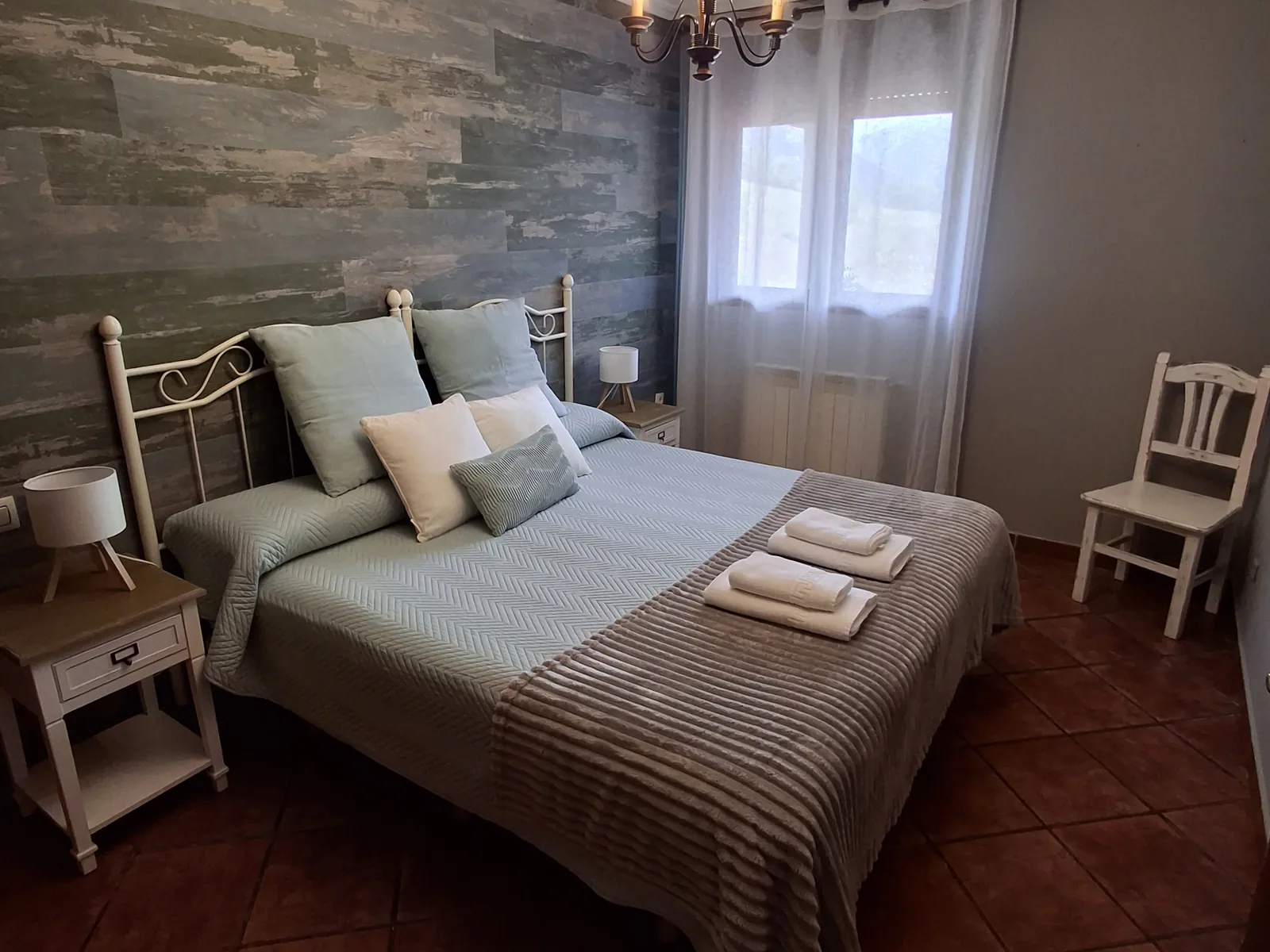 Double bedroom in the Ribeles apartment, with a timber-clad wall behind the bed