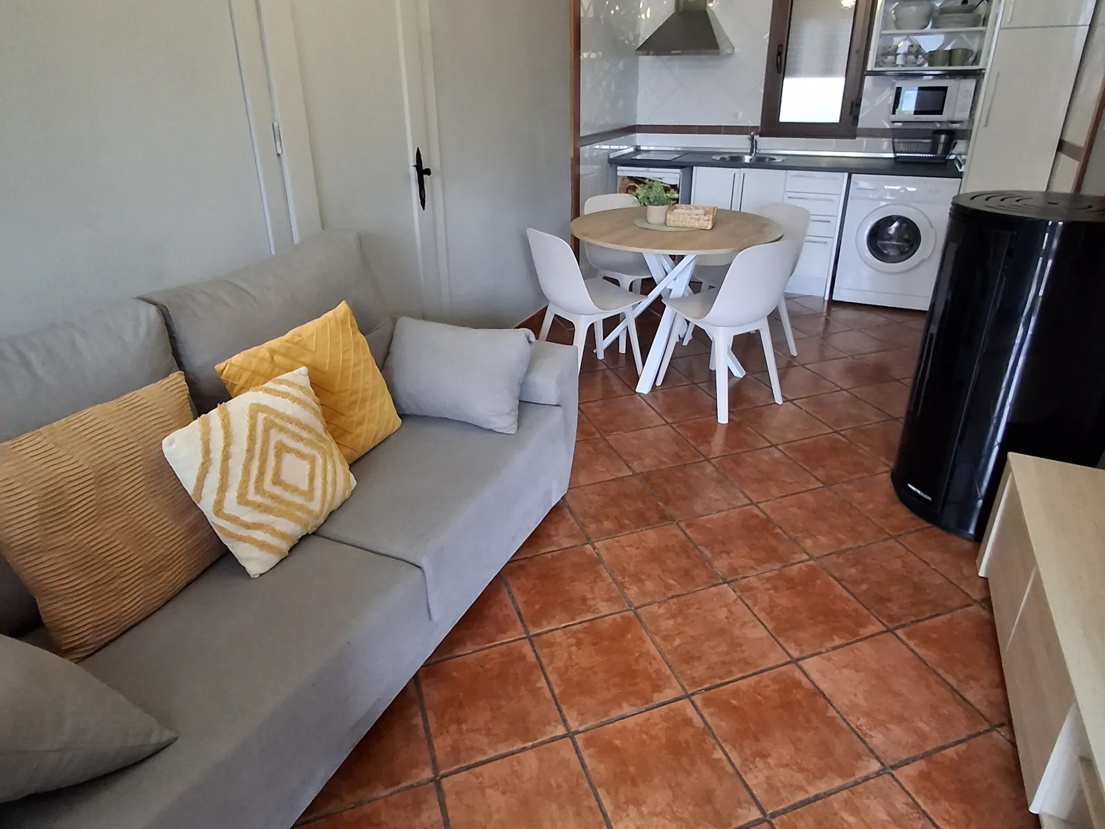 Living room of the Ribeles apartment, with a sofa, a round table and the kitchen behind